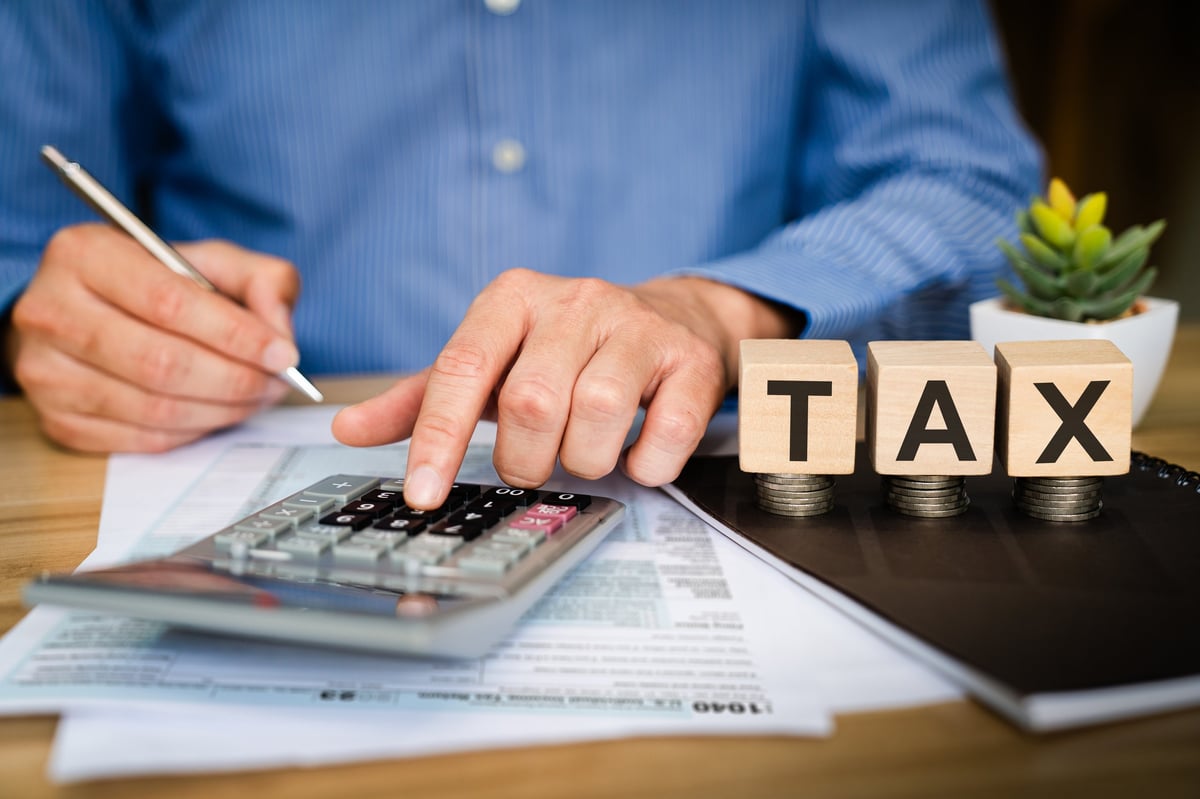 Tax preparer calculating with a calculator and pen on financial documents