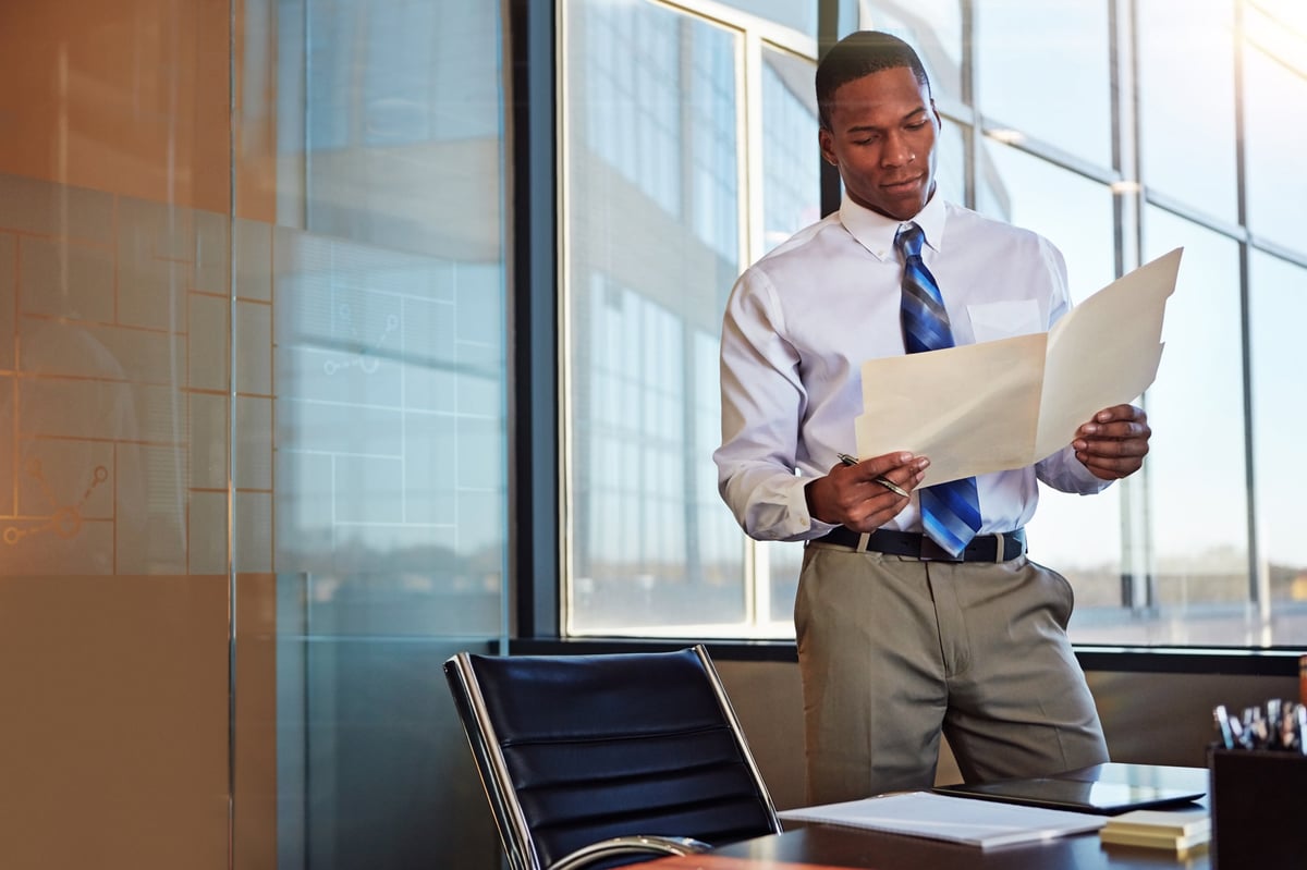Young professional standing by his desk in the office
